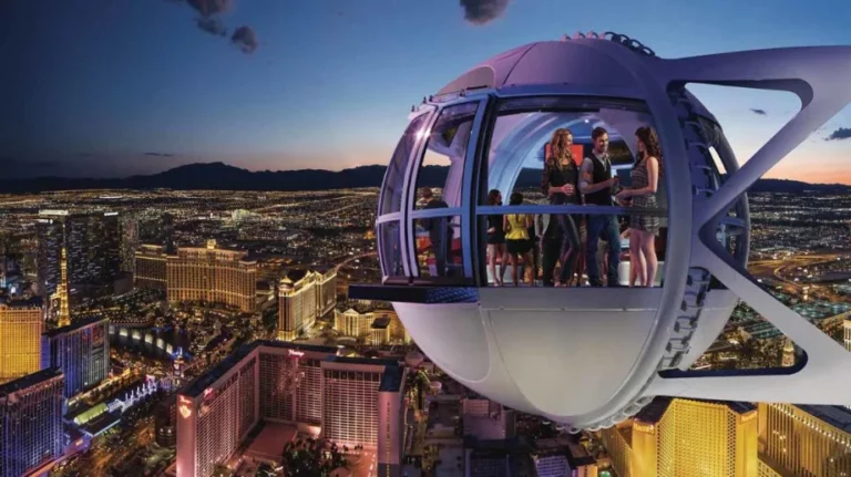 People enjoying a nighttime ride in a High Roller pod in Las Vegas, with a view of the city skyline and brightly lit buildings below
