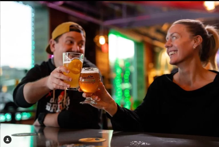Two people enjoying drinks and clinking glasses at a bar, demonstrating team building