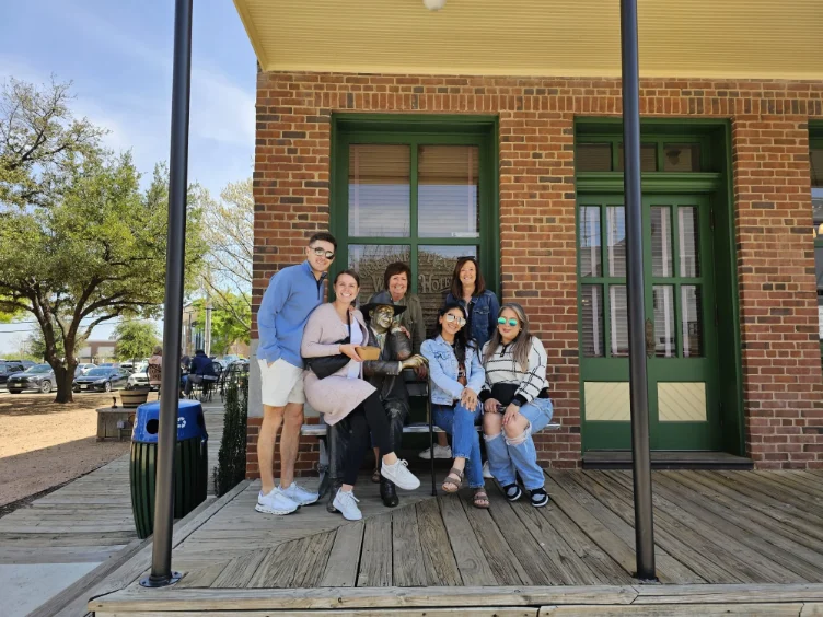Group of people posing outside a building during a wine tour in Grapevine, TX.