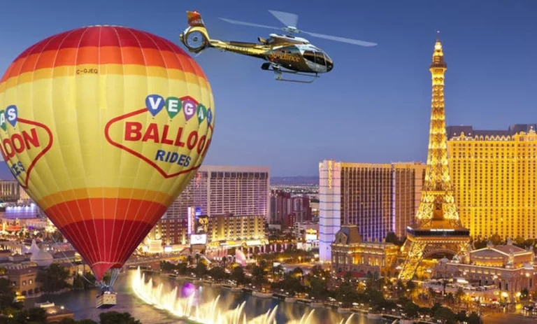 Hot air balloon and helicopter flying over the Las Vegas Strip, featuring the Eiffel Tower replica and city skyline, perfect for a Vegas date night article